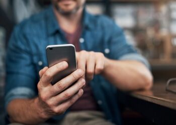 Closeup shot of an unrecognizable designer using a cellphone in an office